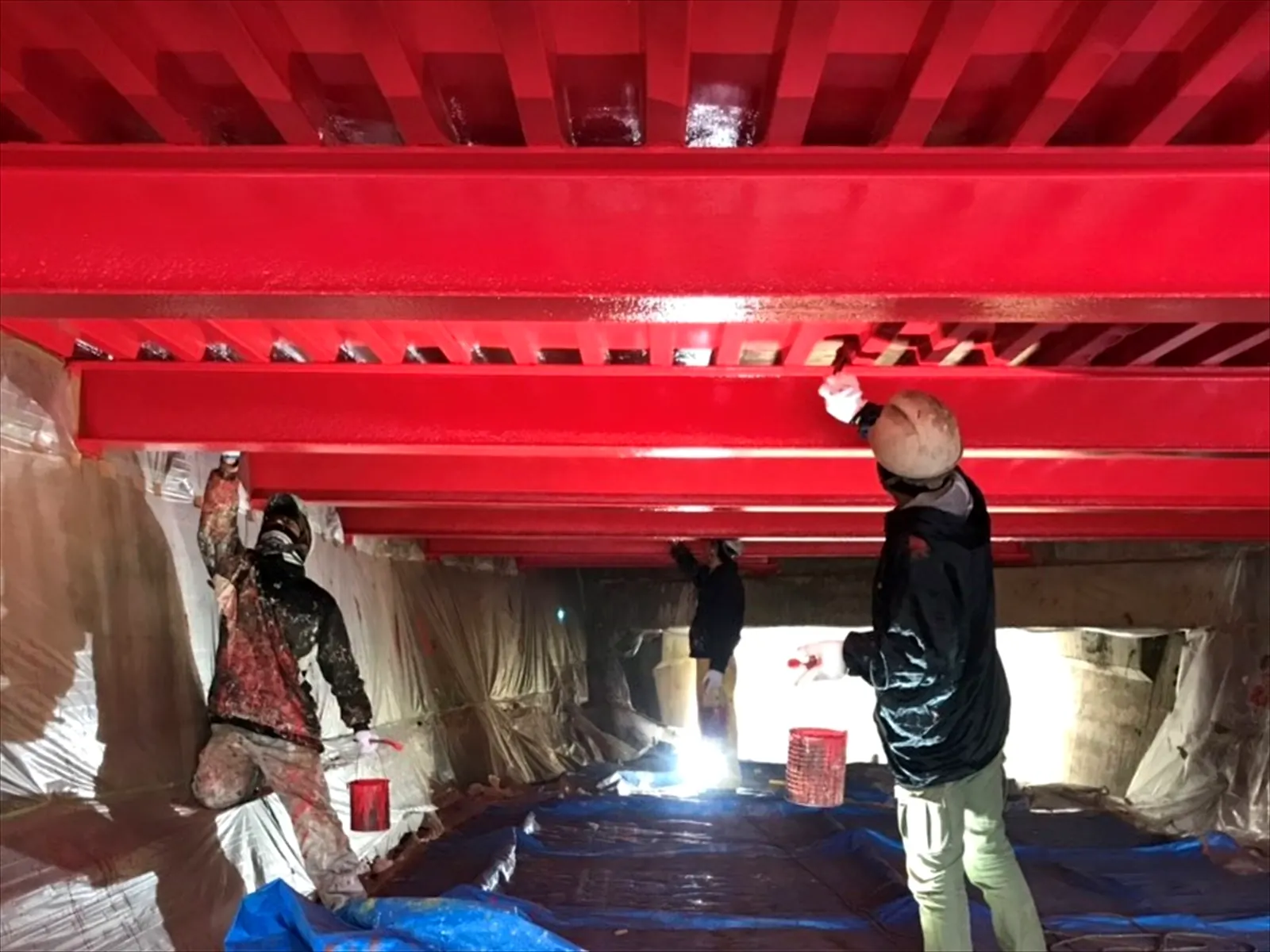 橋桁を赤く塗る職人たち